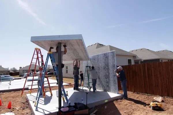 Construction workers pulling a heavy cemented wall